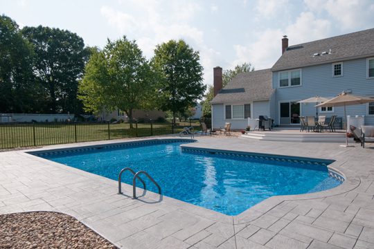 This is a photo of the true-L roman inground swimming pool with black fence installed by julianos