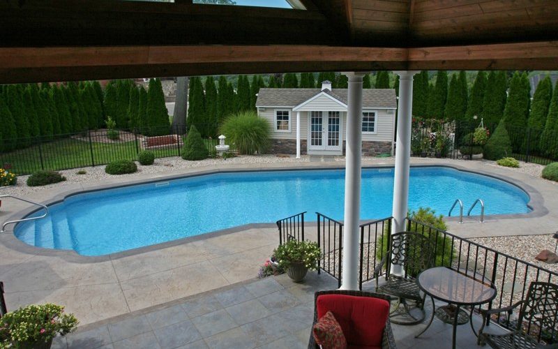 This is a photo of a Lazy L style custom inground swimming pool with custom pool house