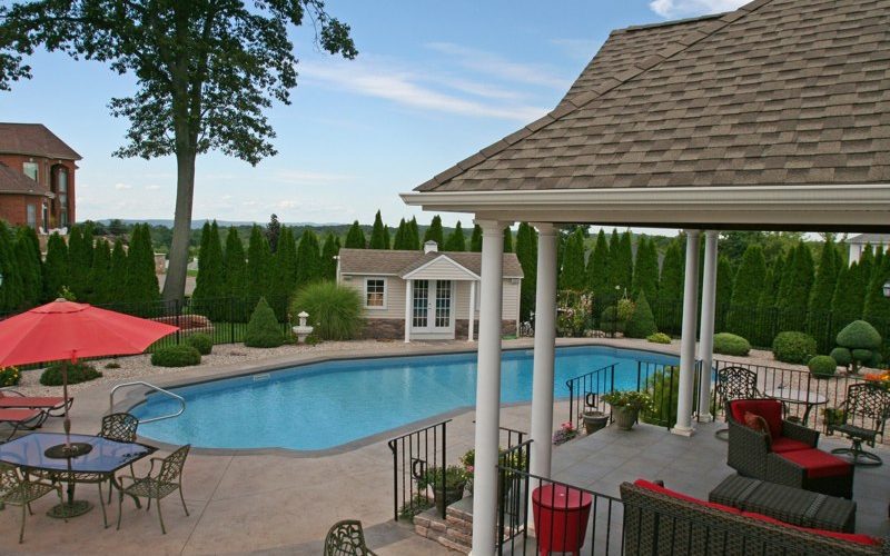 This is a photo of a Lazy L style custom inground swimming pool with custom pool house