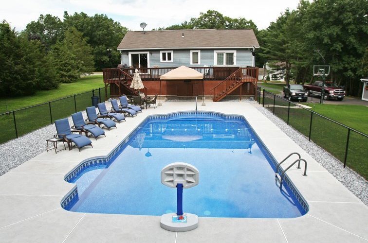 This is a photo of a patrician in ground pool with custom deck and chairs.