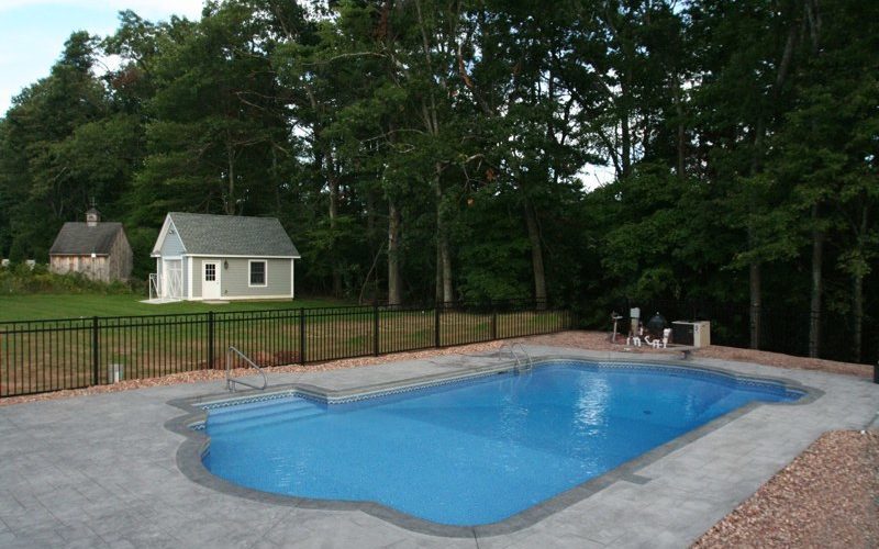 This is a photo of a roman in ground pool in Kinderhook, NY with custom pavers, diving board and steps.