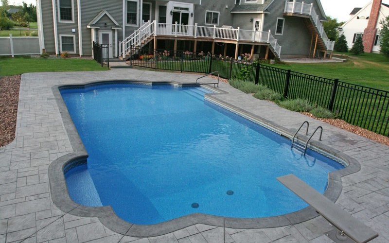 This is a photo of a roman in ground pool in Kinderhook, NY with custom pavers, diving board and steps.
