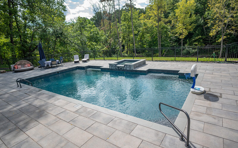 Custom Inground Pool installed by Majestic Pools with outdoor furniture and hot tub